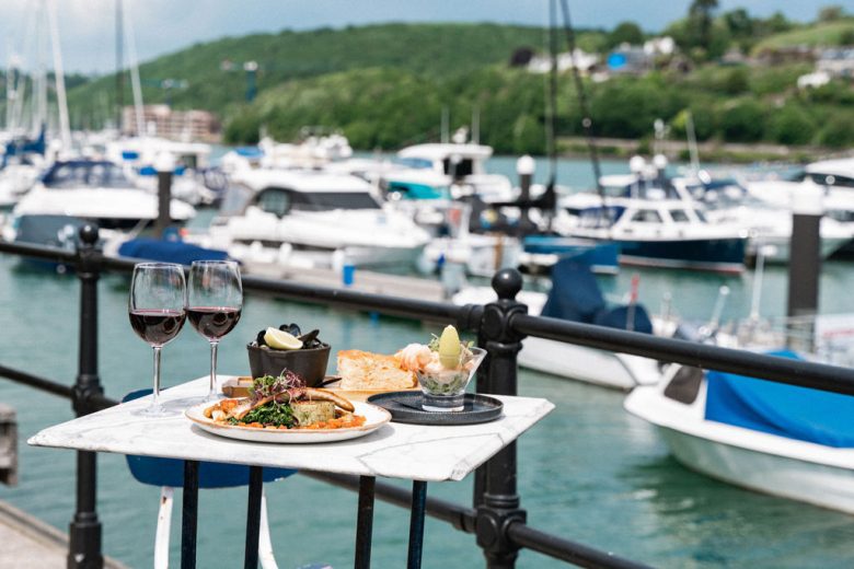 table made up with red wine and seafood dishes by the sea